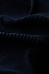 Close-up of dark ribbed fabric texture.  Soft, draped material with subtle shadows creating depth.