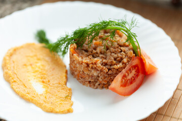 Hearty buckwheat dish with creamy puree and fresh tomato slices.  Garnished with dill for a vibrant presentation.