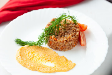 Delicious buckwheat groats with creamy sauce and fresh dill, garnished with tomato slices. A healthy and flavorful meal.