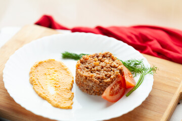 A healthy and delicious buckwheat dish, served with a side of pureed vegetables and fresh tomato slices. A perfect meal for a healthy diet.