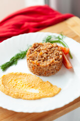 Hearty buckwheat dish with carrot puree and tomato garnish. A healthy and flavorful meal.