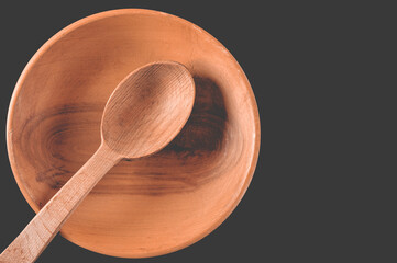 Brown wooden spoon in wooden plate on black table