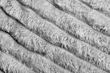 Close up texture of soft, fluffy gray fleece fabric with diagonal folds. Perfect for backgrounds, textile patterns, upholstery, interior design, or cozy-themed creative projects.