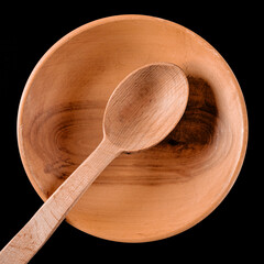 Brown wooden spoon in wooden plate on black table