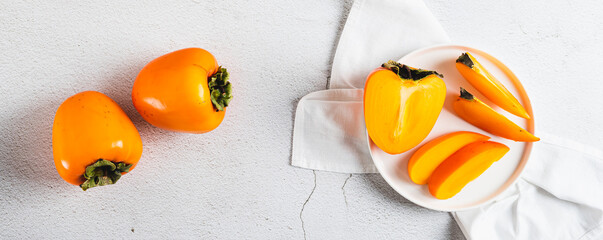 Plate with pieces of sweet tasty persimmon on white background top view web banner