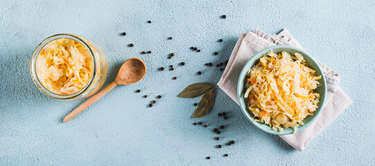 Homemade fermented cabbage in a bowl on the table top view web banner