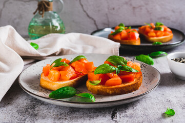 Appetizing bruschetta with tomatoes, garlic and basil on a plate on the table