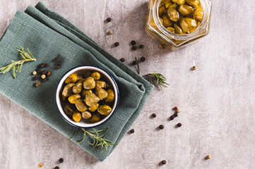 Pickled capers with spices in a bowl and in a jar on the table top view
