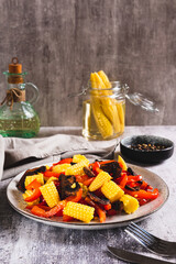 Appetizing salad of canned corn, fried mushrooms and peppers on a plate vertical view