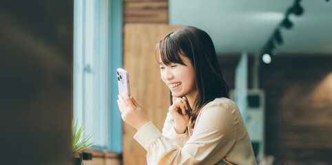 笑顔でスマートフォンを使う女性・ビジネスウーマン