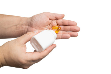 Male hand pouring yellow omega-3 capsules from plastic bottle into a palm, fatty acid, fish oil...