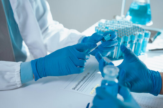 Scientists exchanging test tube in laboratory with test tubes rack and documents