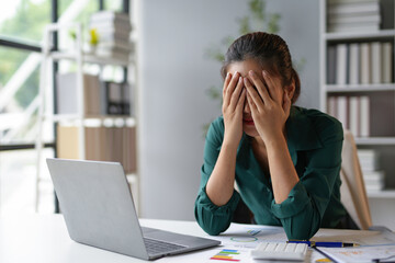 Stressed businesswoman covering her face with hands at office desk