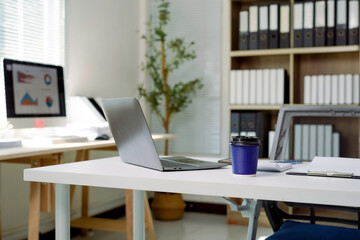 Modern office desk with laptop showing financial charts on screen
