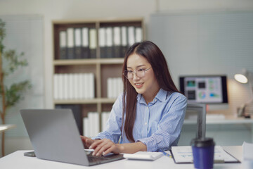 Fototapeta premium Young Asian businesswoman working on laptop in modern office