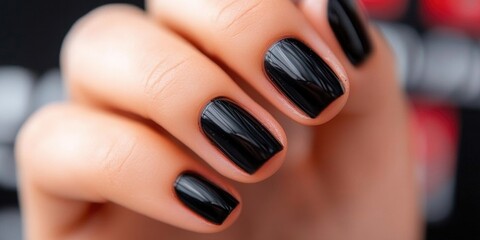 Fototapeta premium Glossy black manicure on female hand with short nails close-up
