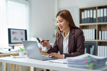 Asian businesswoman using laptop and explaining financial charts in office