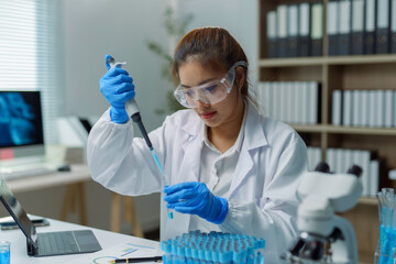 Fototapeta premium Scientist dropping blue liquid in test tube using micropipette during experiment in laboratory