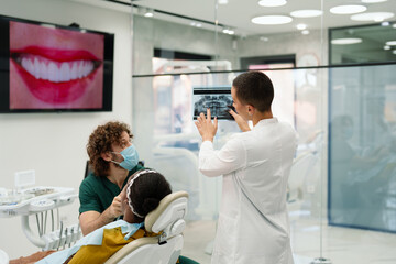 Dentist Analyzing X-rays with Patient and Assistant