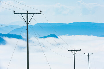 Power lines stretching across mountainous landscape in Norway above clouds