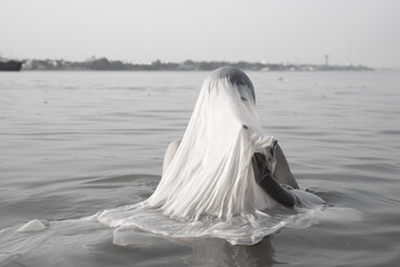 An Indian man taking a holy dip in the river ganges during early morning. 