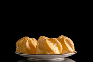 Eclairs on a ceramic saucer, macro, isolated on a black background.