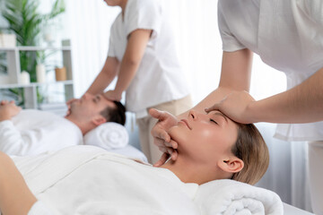 Fototapeta premium Caucasian couple enjoying relaxing anti-stress head massage and pampering facial beauty skin recreation leisure in dayspa modern light ambient at luxury resort or hotel spa salon. Quiescent