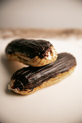 Chocolate eclair with a custard cream filling on a white plate