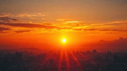 Fototapeta premium Bright orange sunlight descends behind a city skyline, illuminating the clouds with warm colors