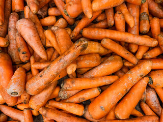 There is a sizable pile of fresh carrots, arranged neatly as they sit on top of each other. These vibrant orange vegetables are ready to be used in various dishes or enjoyed raw