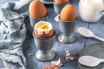Boiled brown eggs in gray egg cups on gray background