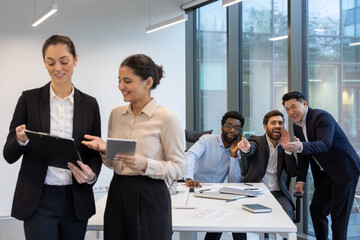 Unethical behavior, harassment. Men mocking female colleagues inside the office.