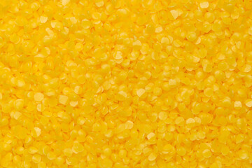 Top view of yellow beeswax pellets, ideal for candle making or crafting. Smooth texture, wax background.