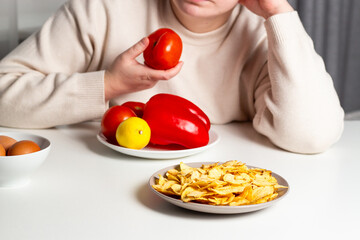 Unhappy woman on diet time eating vegetables. Tired of healthy food. Unsatisfied emotional...