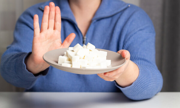 Woman pushes away plate with sugar choosing healthy living. Addiction to sugar concept. Dieting and weight loss. - Powered by Adobe