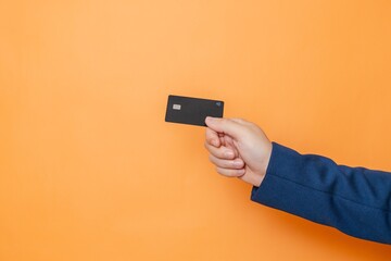 Businessman's hand holding blank credit card with online service for mockup on orange background....