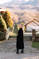 Autumn portrait of a blonde woman in fashionable burgundy clothes walking on the street against the background of a country house outdoors. Selective focus