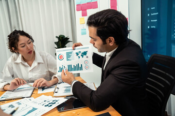 Diverse group of business analyst team analyzing financial data report. Finance data analysis chart and graph dashboard show on TV screen in meeting room for strategic marketing planning. Habiliment