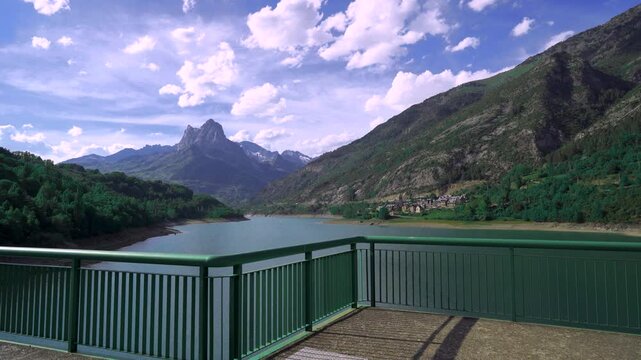 Paisaje de un lago con monta&ntilde;as al fondo y un pueblo un d&iacute;a soleado con cielo azul, nubes y con movimiento de c&aacute;mara. Desde los Pirineos, Lanuza, Sallent de G&aacute;llego, Huesca, Arag&oacute;n, Espa&ntilde;a, Europa.