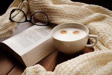 Warm cup of coffee, open book, beige soft warm blanket and glasses. Cozy sweet home atmosphere. Нygge lifestyle concept. Cozy fall mood © AFilipczuk