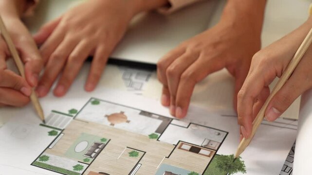 Smart architect and safety engineer discussion about building blueprint on table with architectural document, measurement tools and wooden block scatter around at modern office. Closeup. Delineation.