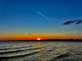 inversion trail on the sunset sky over the sea