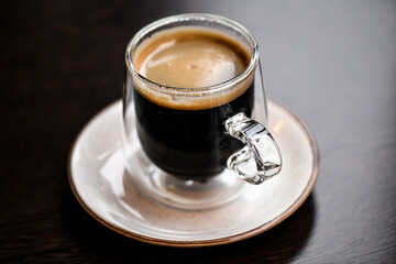 Espresso in a clear double-walled glass cup on a saucer