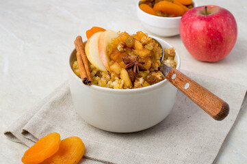 Bulgur with apple and cinnamon in a bowl. Sweet porridge with dried fruits for breakfast. Horizontal.