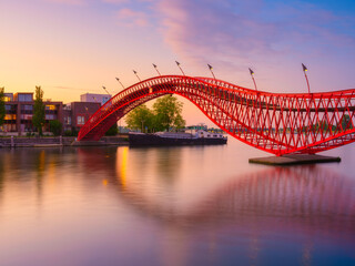 The Python Bridge, Amsterdam, the Netherlands. The bridge on the blue sky background during the blue hour. Dutch canals. Photo for background, wallpaper, postcards.