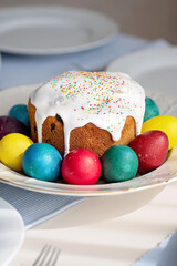 Easter cake decorated with icing and sprinkles, surrounded by colorful eggs on festive table setting