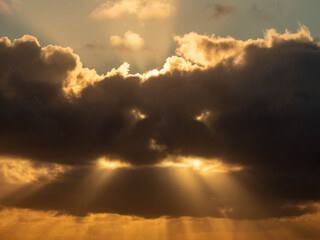 Scary monster like dark cloud with eyes and light rays shining through a mouth. Frightening nature background. Abstract horror cloudscape.