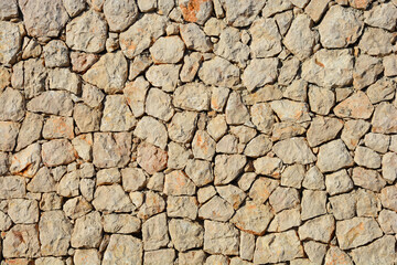A wall made of natural, irregularly shaped stones, creating a rustic and textured surface