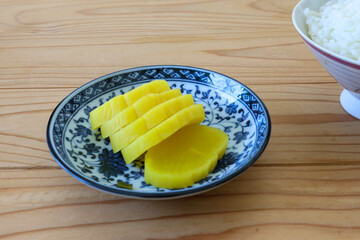 木材背景の皿にのせた沢庵