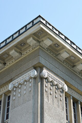 Obraz premium A building corner featuring decorative elements, columns, and facade details against a blue sky